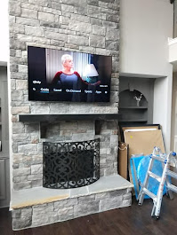 65-inch TV mounted on stone fireplace in Woodstock, GA with MantelMount pull-down bracket
